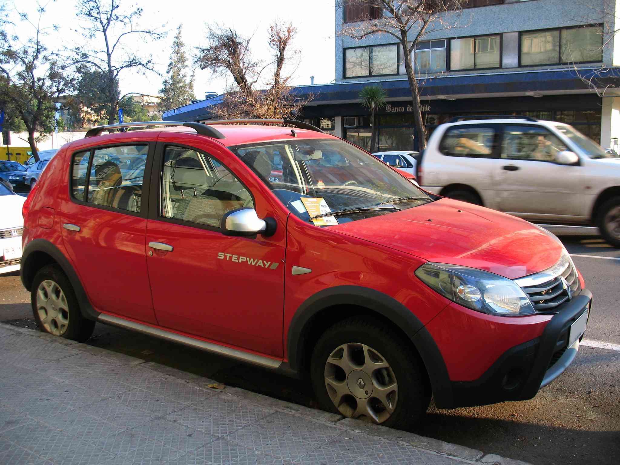 Красная Рено Сандеро припаркована у тротуара